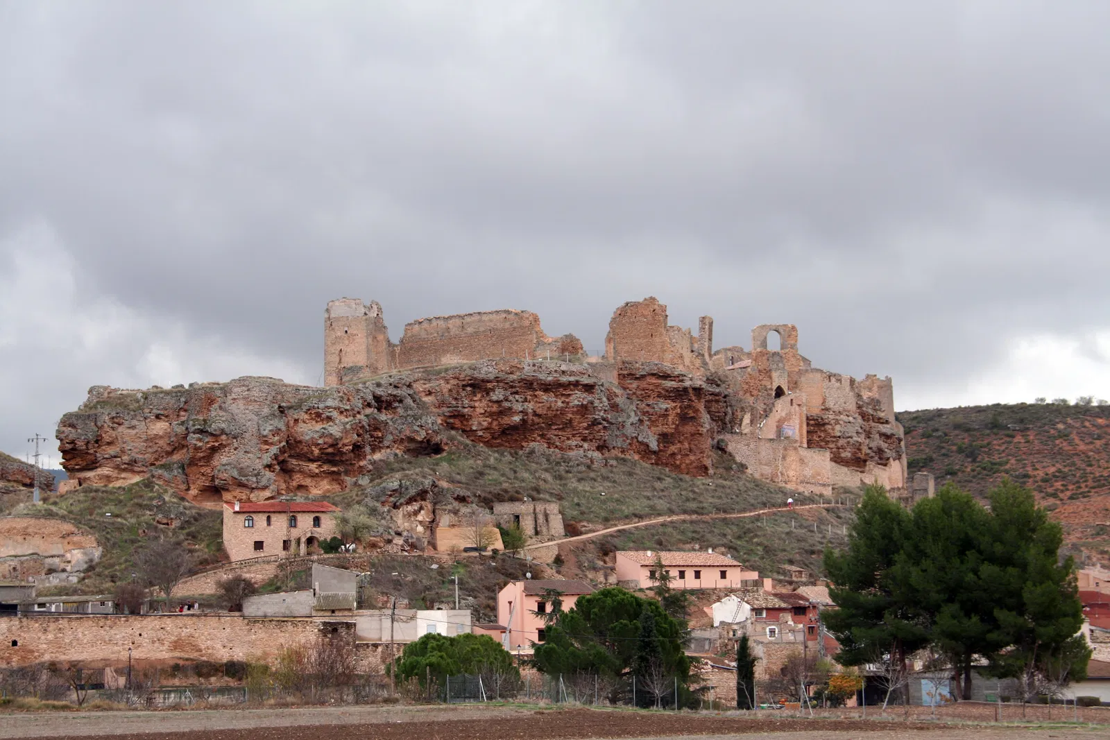 Vista horizontal del pueblo de Almonacid de Zorita con una iglesia o castillo en ruinas en lo alto, rodeado de vegetación