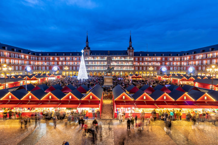 Mercadillo navideño Plaza Mayor Madrid con casetas rojas, luces y ambiente festivo en el centro histórico.